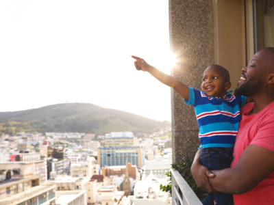 Man holds young son as sun sets behind them
